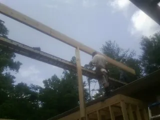 Carpenter setting a ridge beam over a new addition frame — Ice Dam Removal by Roofing Brothers in Schulenburg