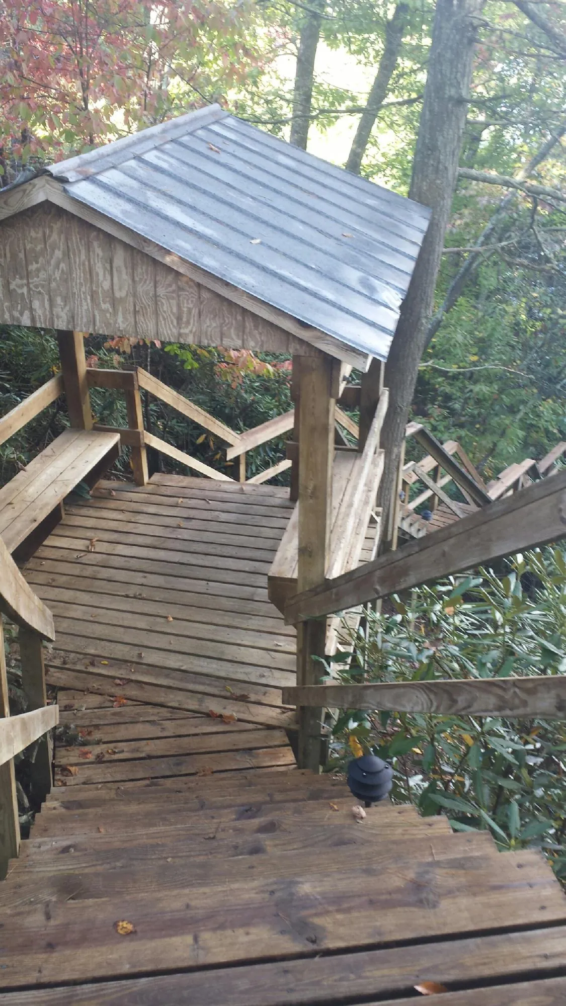 Metal roofed shelter over wooden steps on a wooded walkway — Skylight Repair & Installation work by our crew in Schulenburg