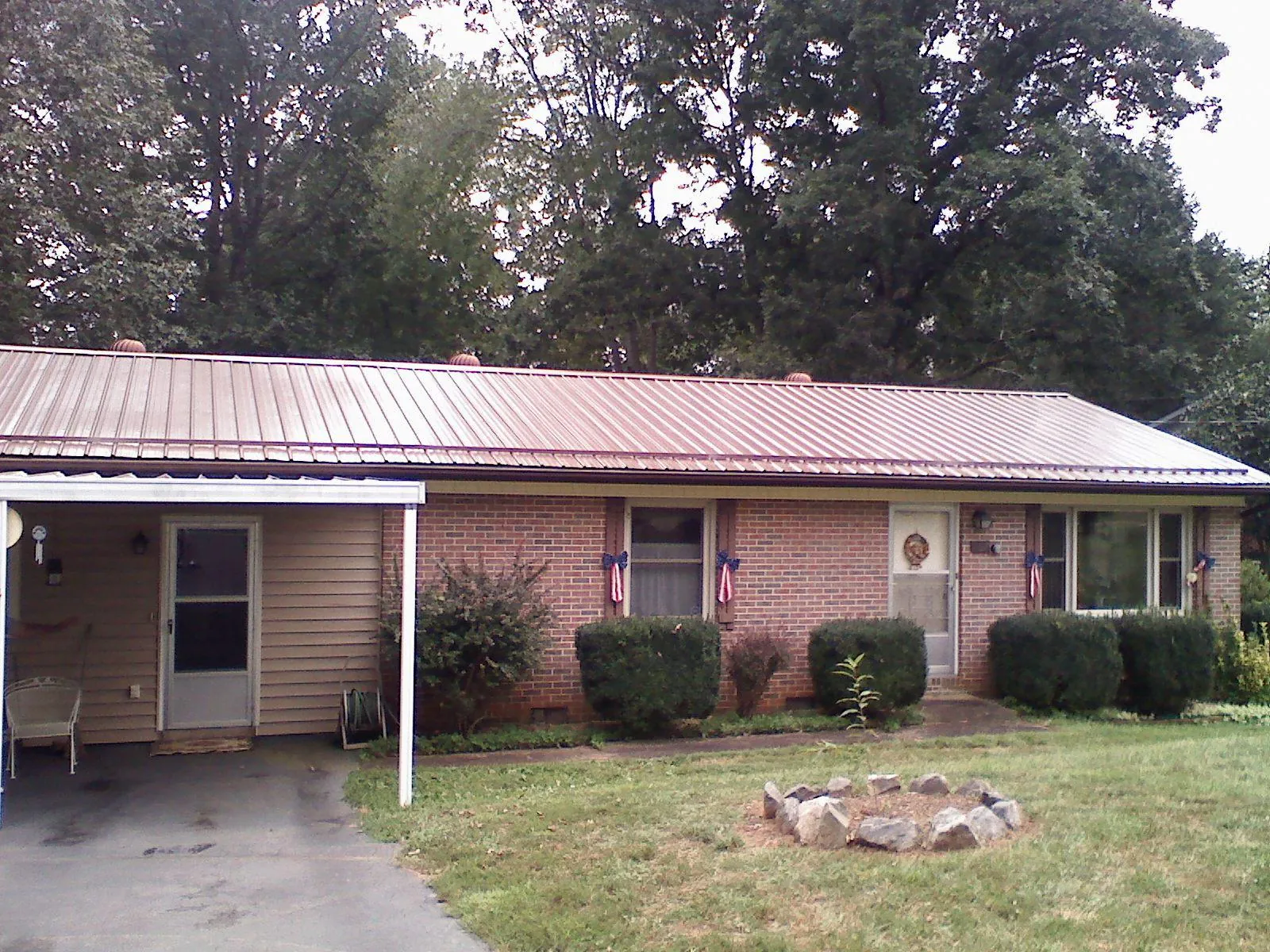 Bronze metal roof and carport on a brick ranch home — Roof Repair work by our crew in Schulenburg